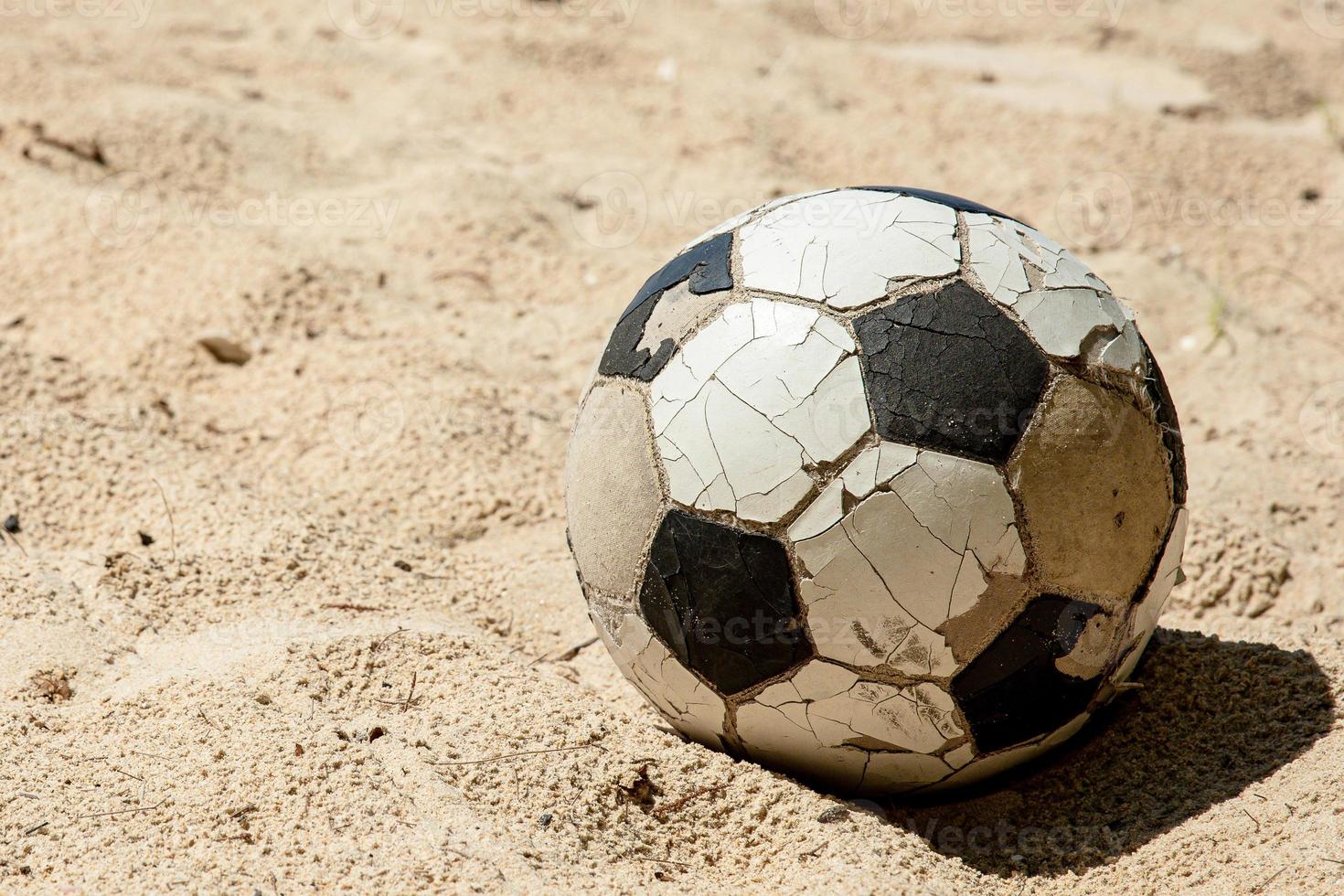 centrar una sola bola en la playa sin nadie. bola clásica rota en la arena. resumen de la afición y la vida deportiva. foto