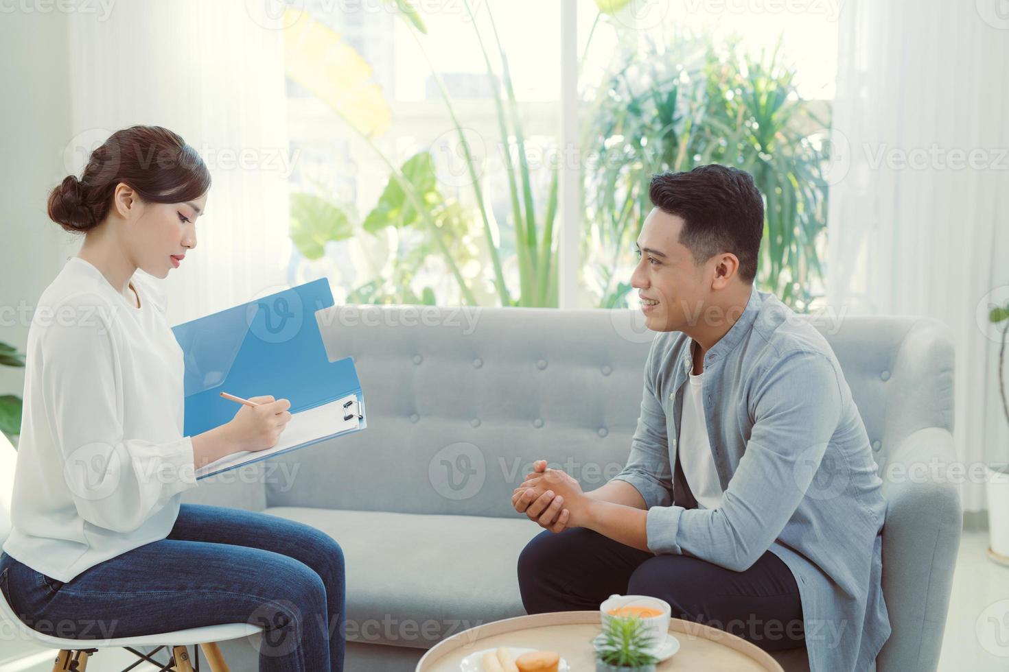 Psychologist listening to her patient and writing down notes, mental health and counseling concept photo