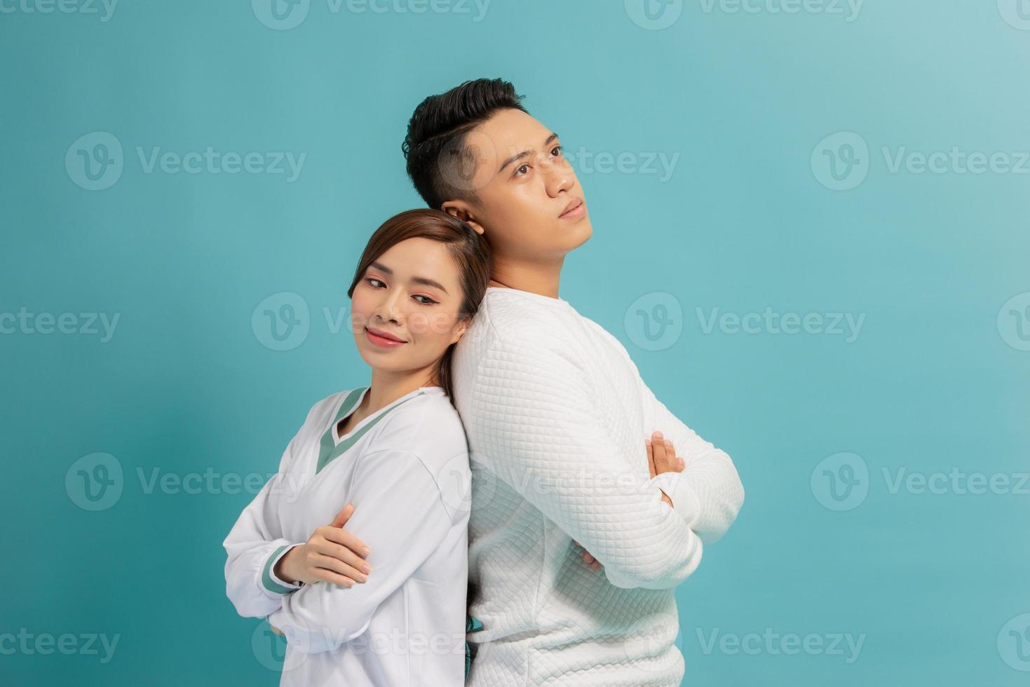 Studio photo of lovely glad couple keeping hands crossed on their chests and laughing happily standing over blue background