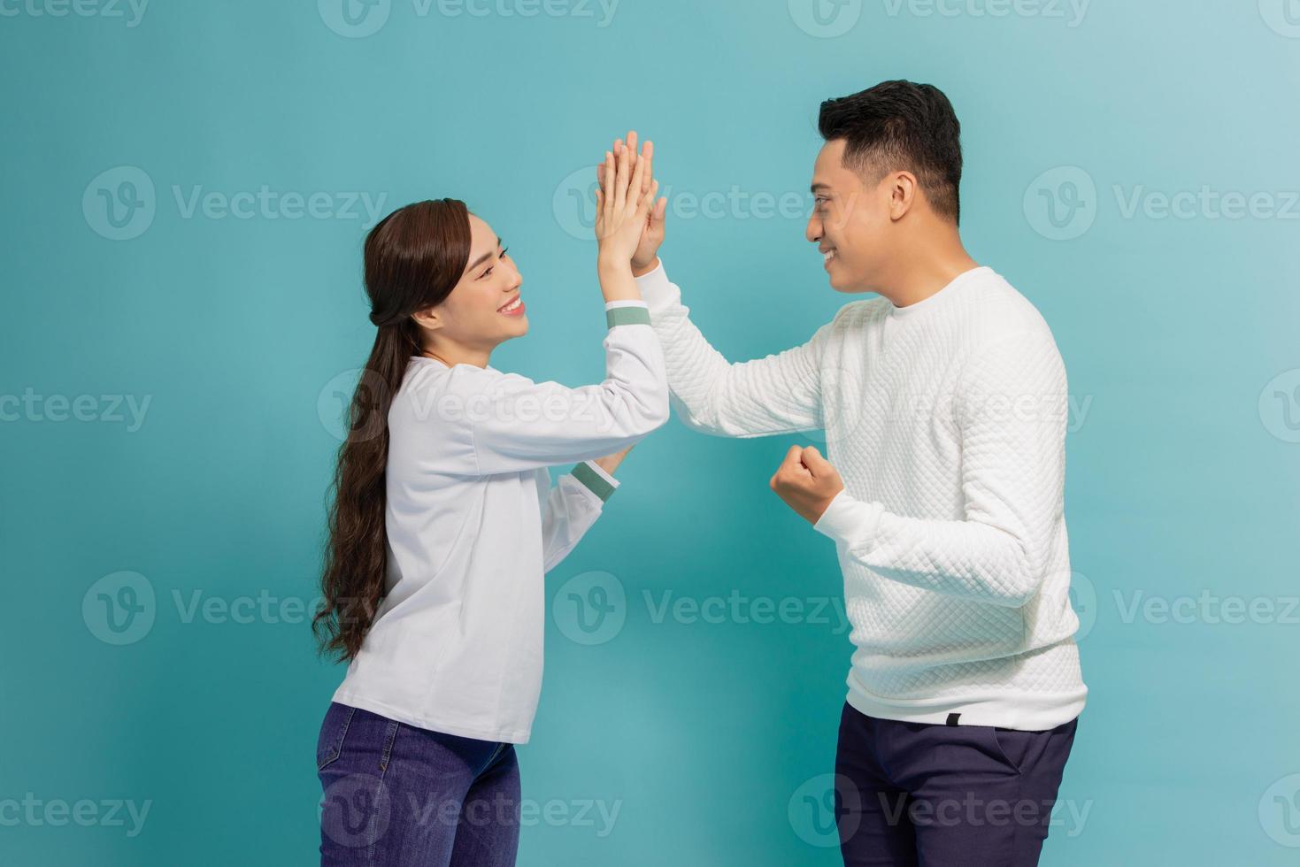 Portrait of a cheery young couple giving high five over blue background photo