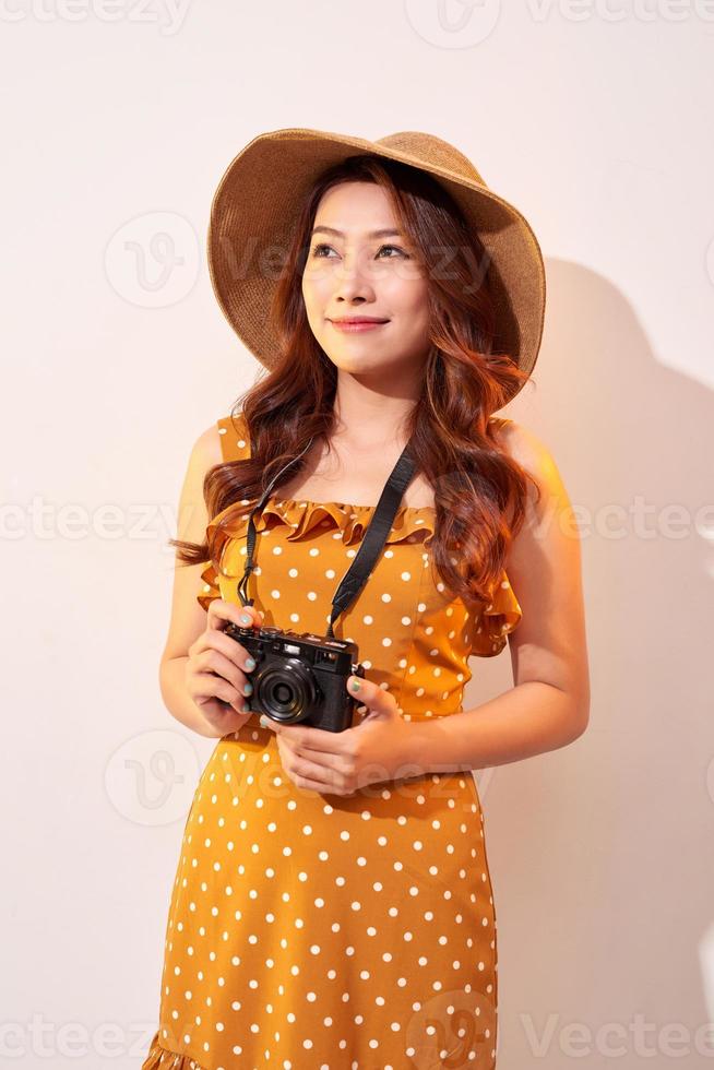 Image of young photographer woman isolated over beige background wall holding camera. photo