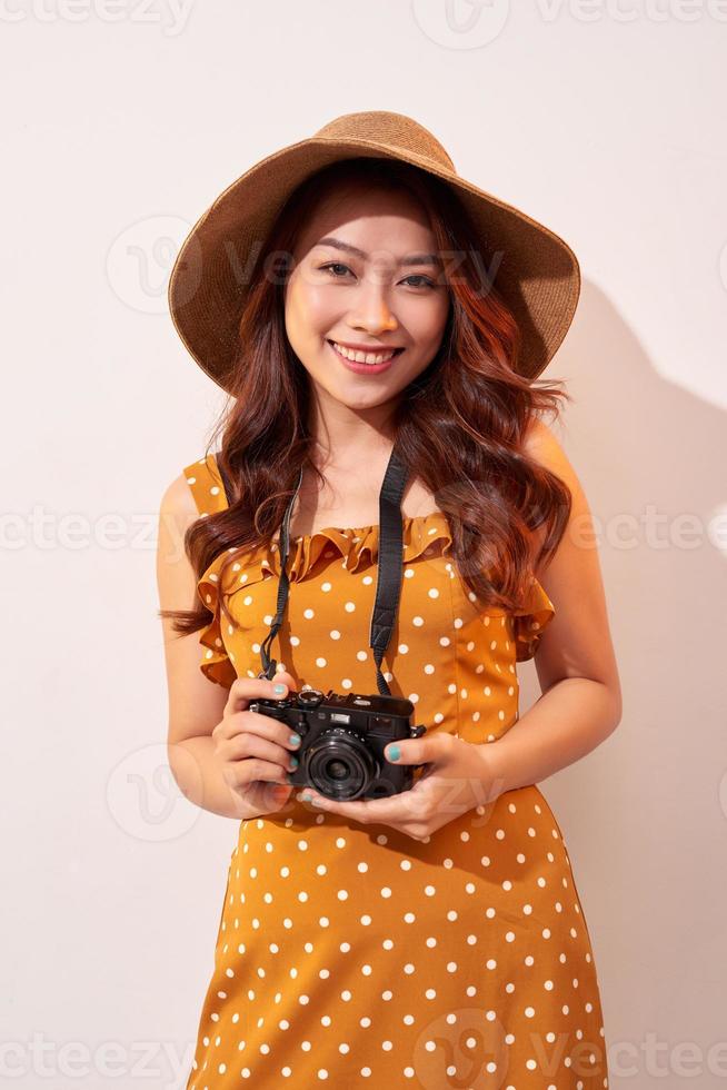 Image of young photographer woman isolated over beige background wall holding camera. photo