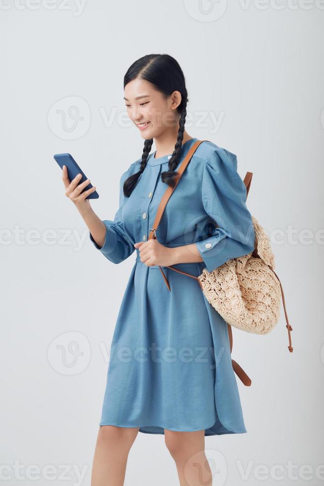 Studio shot of young happy Asian woman smiling while using mobile phone photo
