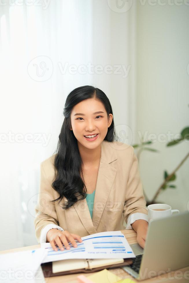 Young female gardener in glasses using laptop, communicates on internet with customer in home photo