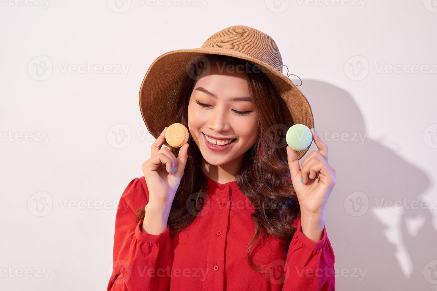 Young woman standing with french sweet cookie macaron over white background photo