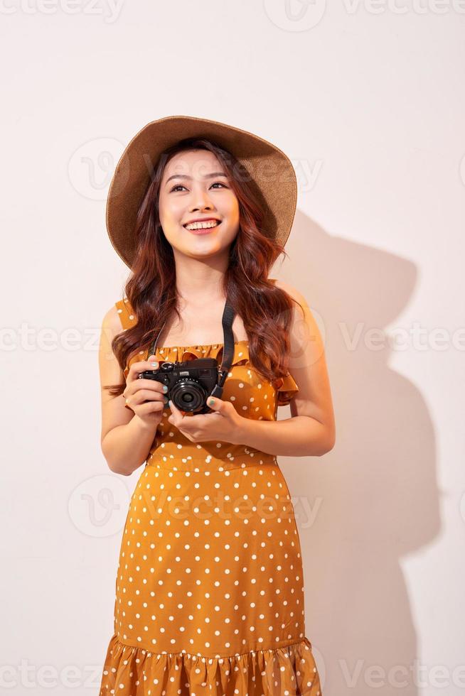 Image of young photographer woman isolated over beige background wall holding camera. photo