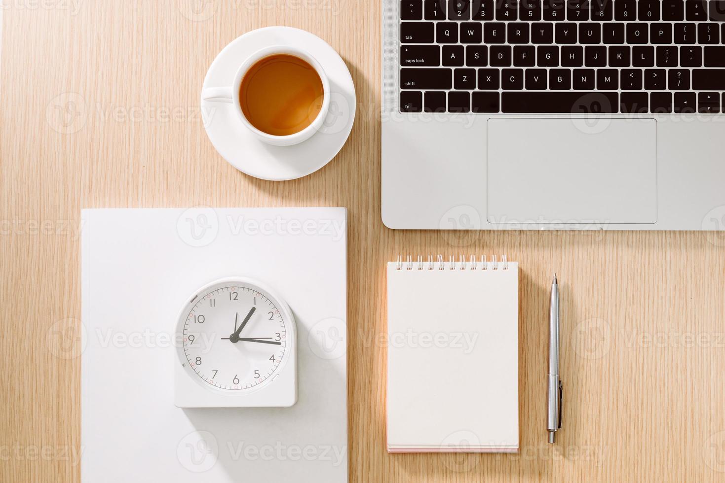 mesa de escritorio de oficina con computadora portátil, teléfono inteligente, taza de café, bolígrafo, lápiz y cuaderno. artículos de oficina y aparatos en la mesa del escritorio. concepto de mesa de escritorio de trabajo. foto