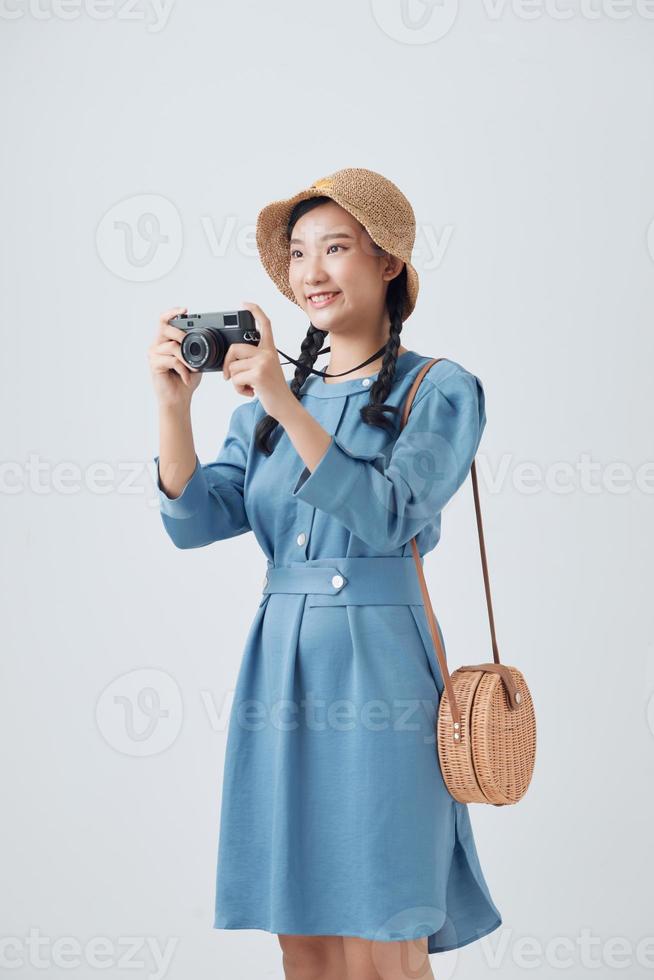 Portrait of a smiling young woman in summer hat standing with photo camera isolated over white background
