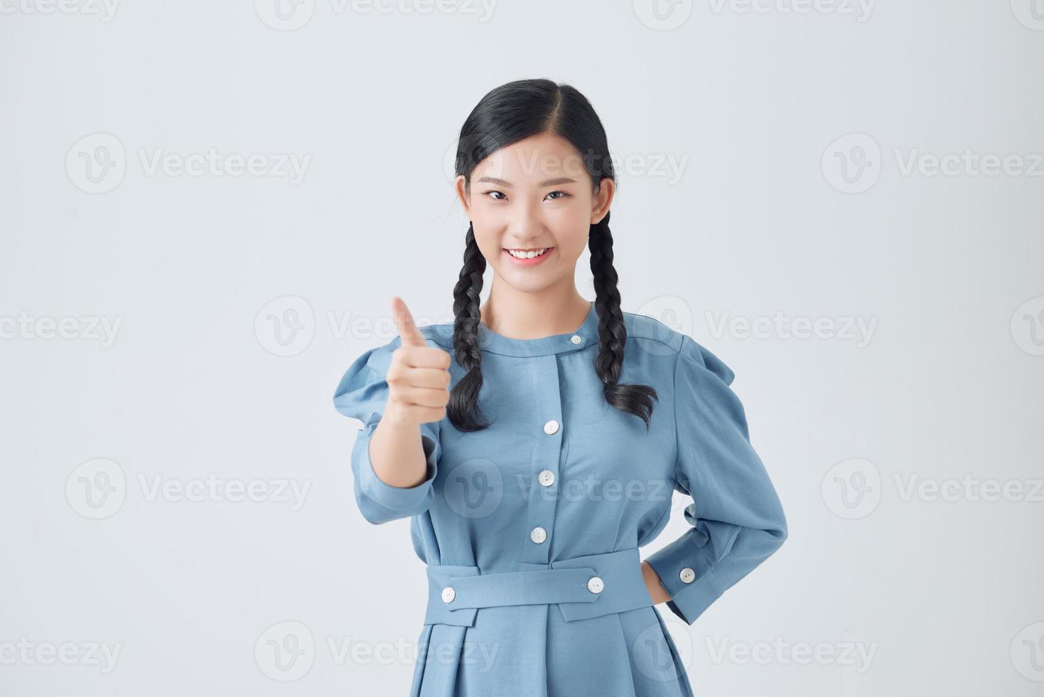 Excited pretty asian teenager holding thumbs up isolated over white background. Concept of positive evaluation. photo