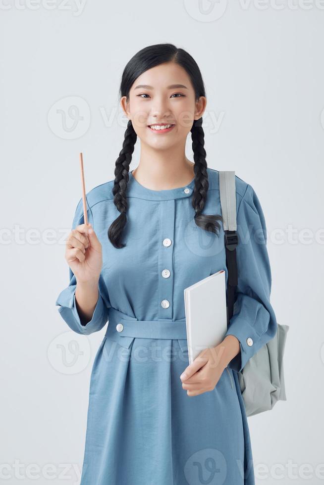 attractive female student smiling holding a bunch of notebooks in one hand and a pencil in another photo