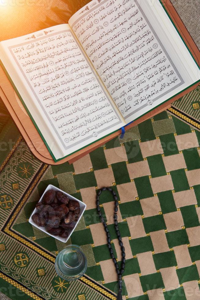 iftar time dátiles secos, vaso de agua del sagrado corán y tasbih en la alfombra de oración sarajevo foto