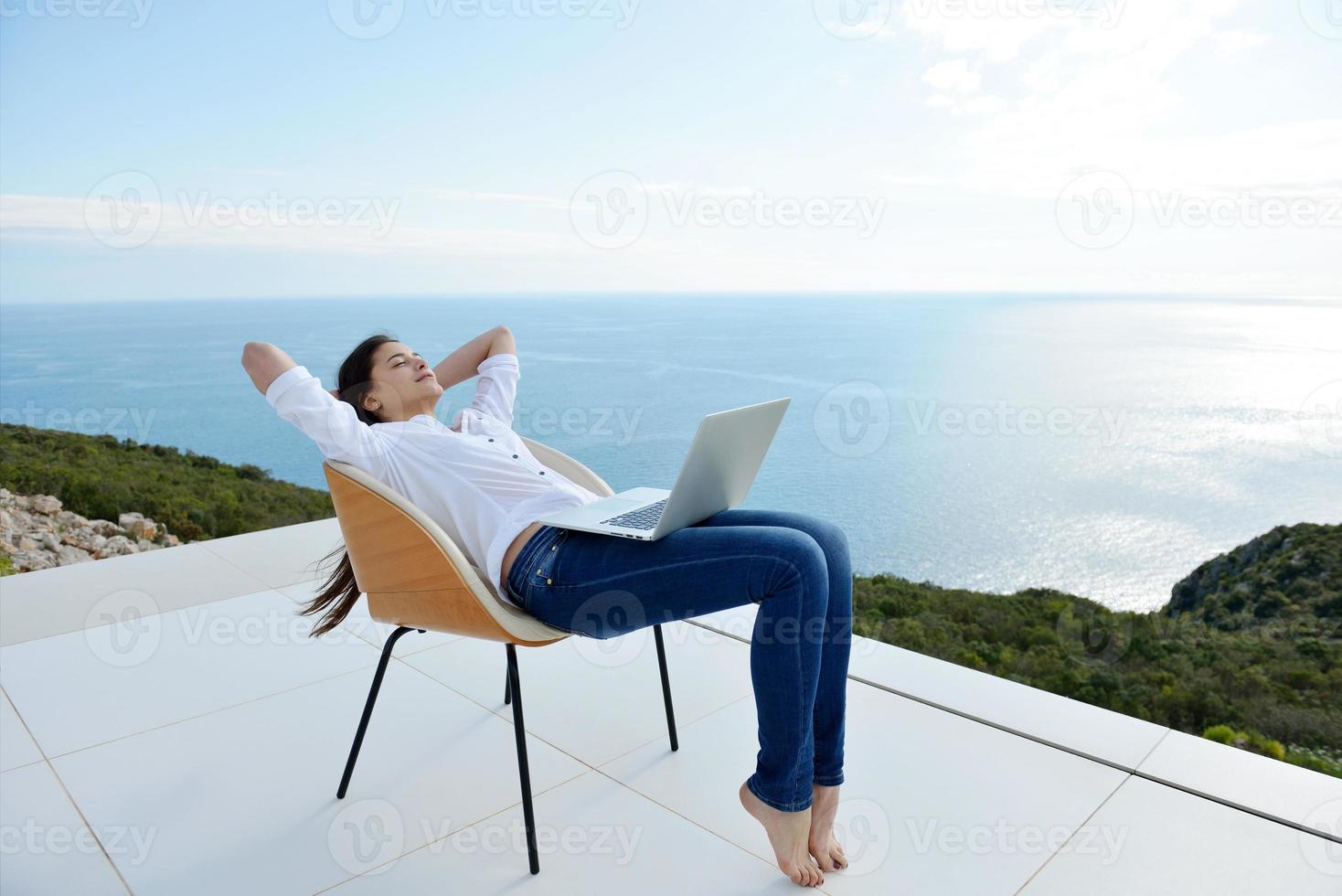 relaxed young woman at home working on laptop photo