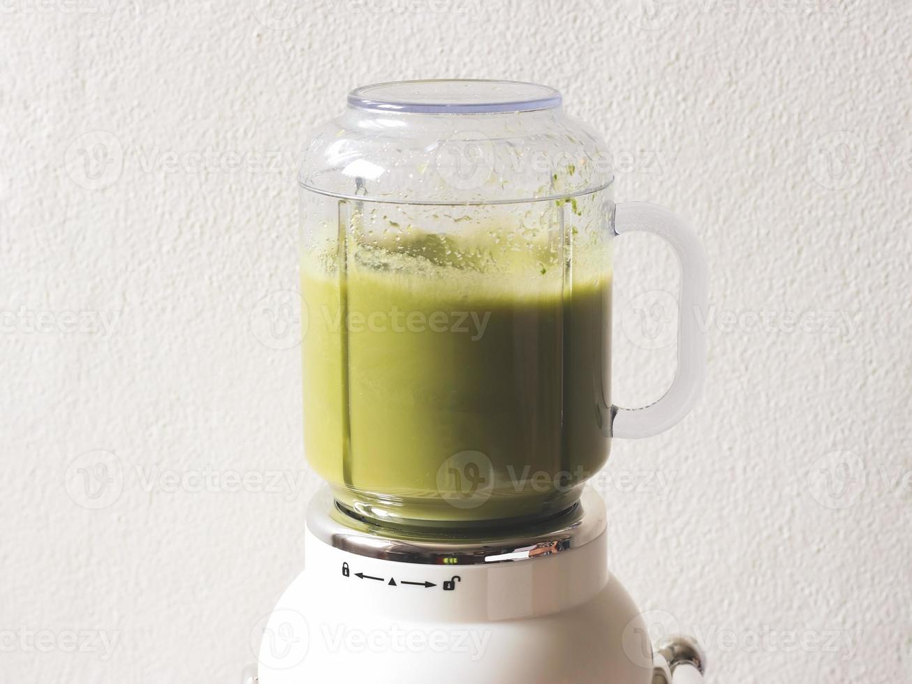 white vintage blender or smoothie maker machine working on making smoothie  on  black and white stripe table cloth and white wall. Healthy drink making. photo