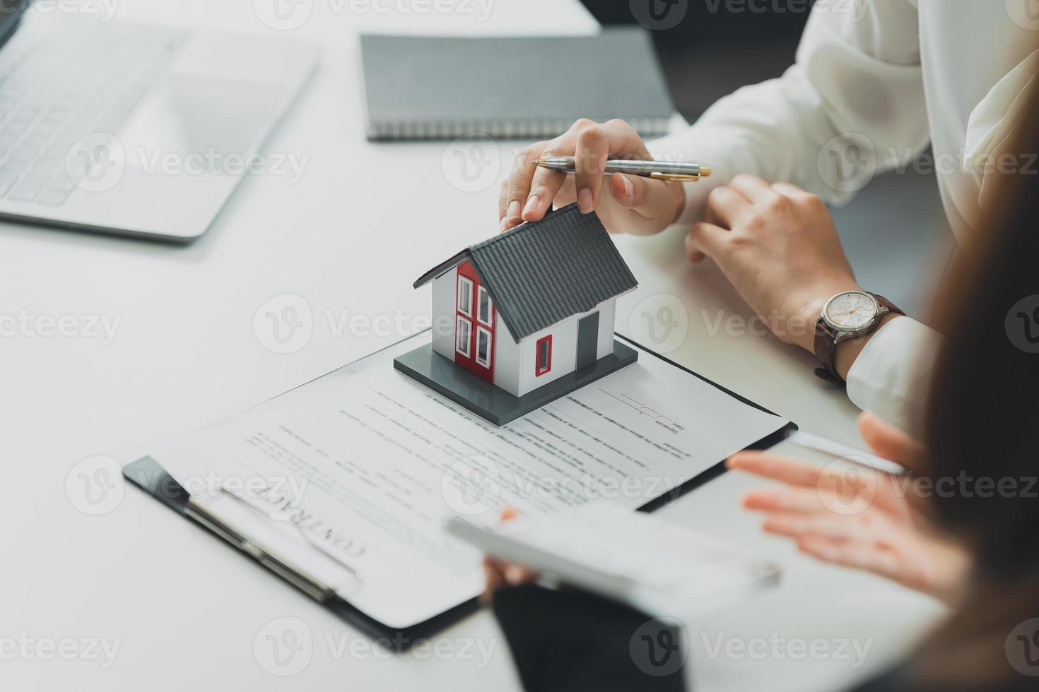 el banquero o el agente calculan el precio de la casa de compra o préstamo y se lo muestran al cliente. concepto de bienes raíces. foto
