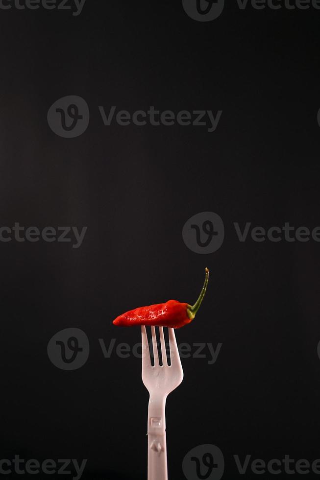 premium chili in the fork with black background photo