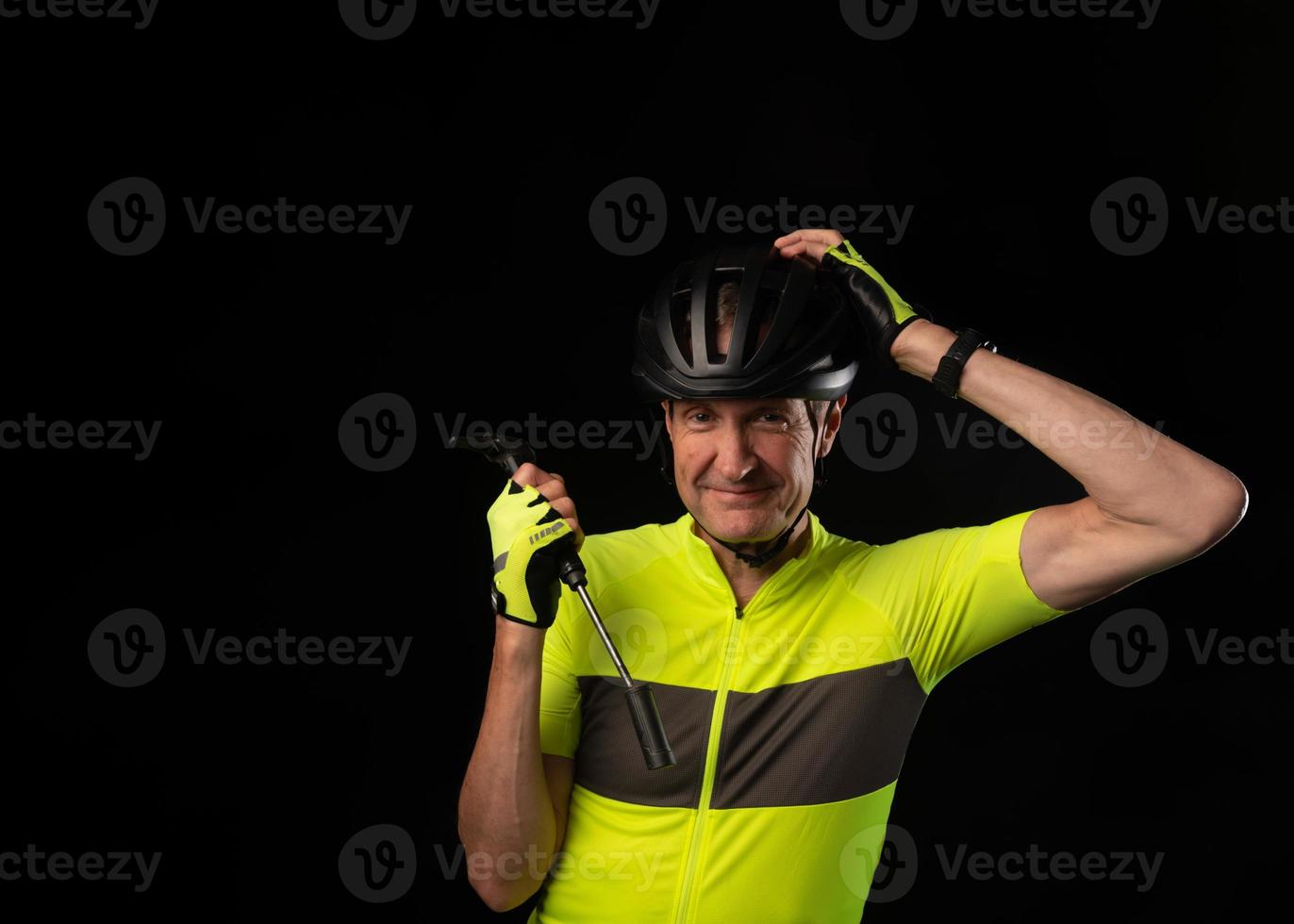 Elderly cyclist with hand on head holding a bicycle pump photo