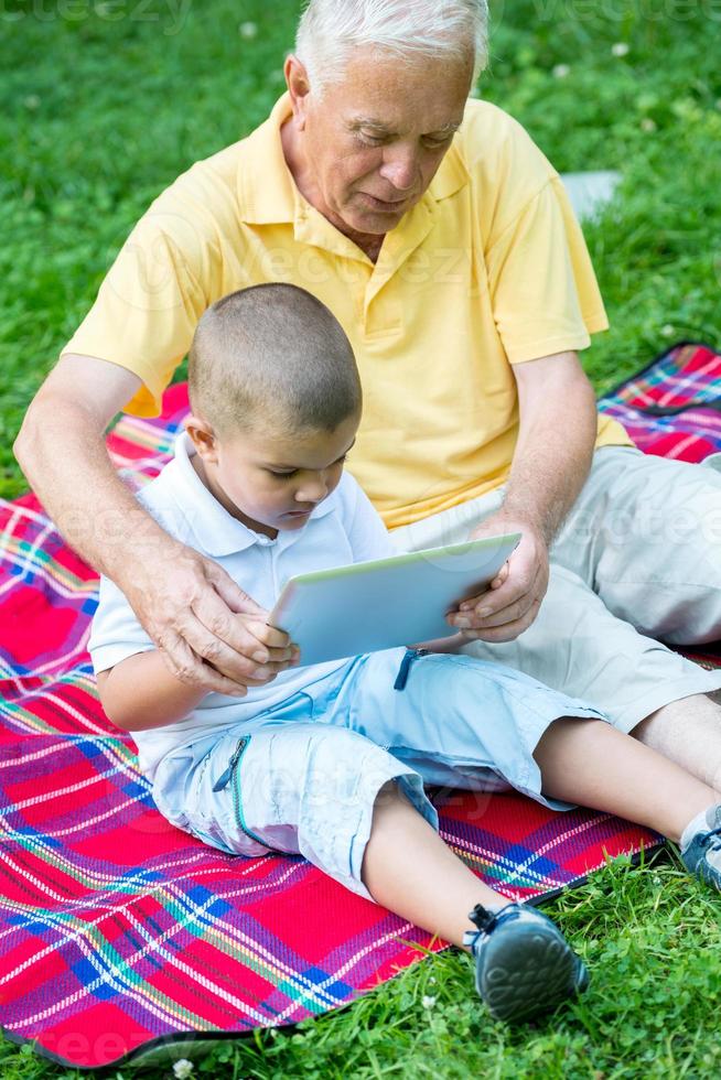 abuelo y niño en el parque usando tableta foto