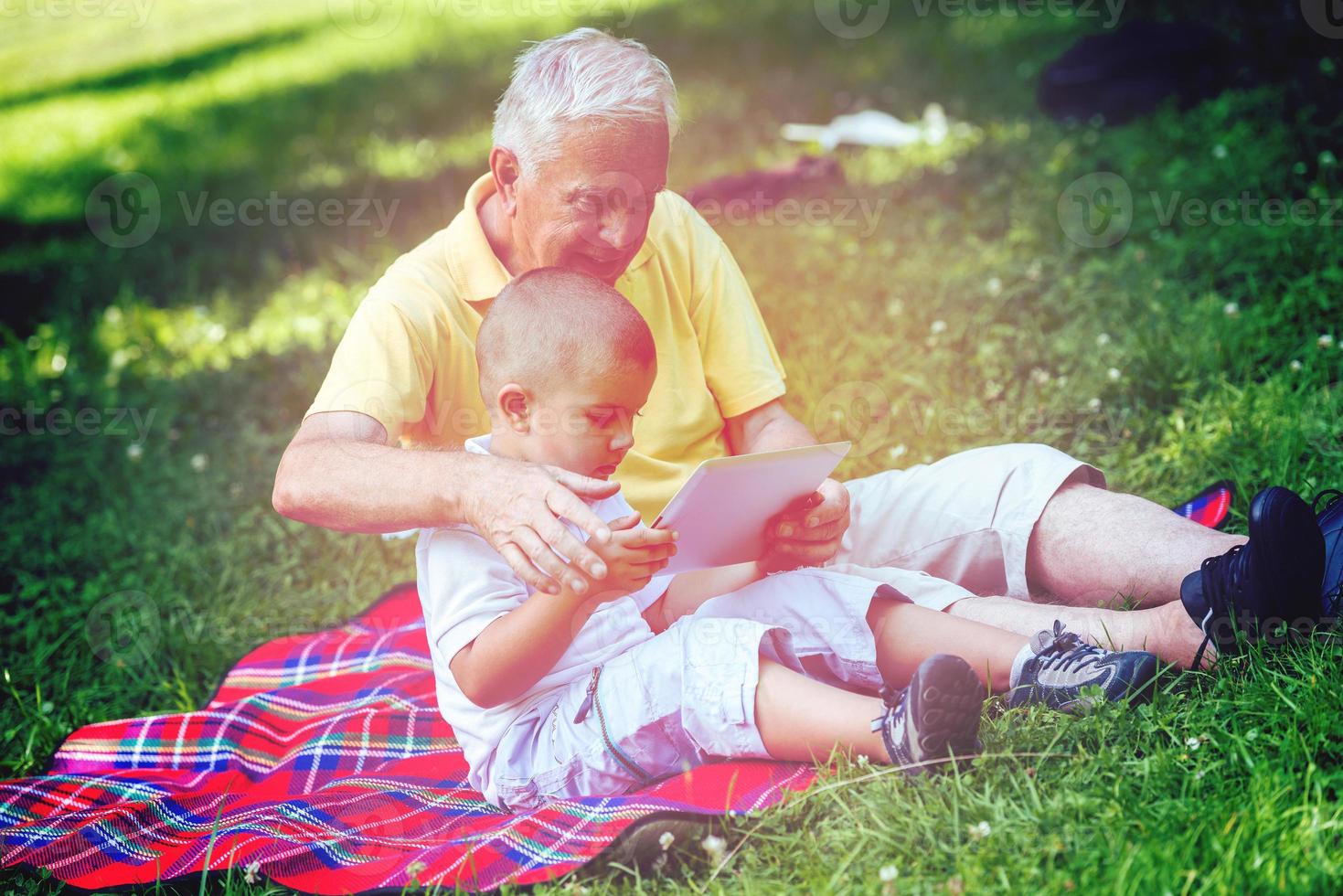 grandfather and child in park using tablet photo