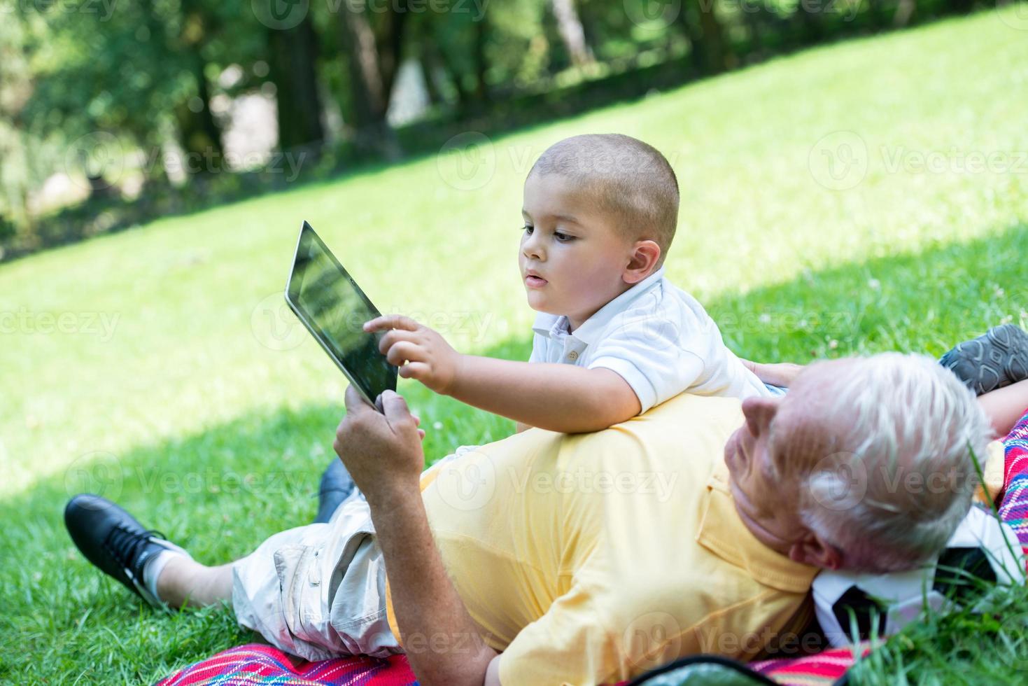 grandfather and child in park using tablet photo