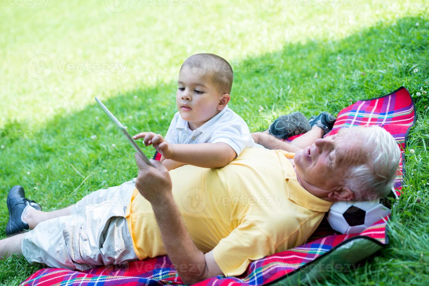 grandfather and child in park using tablet photo