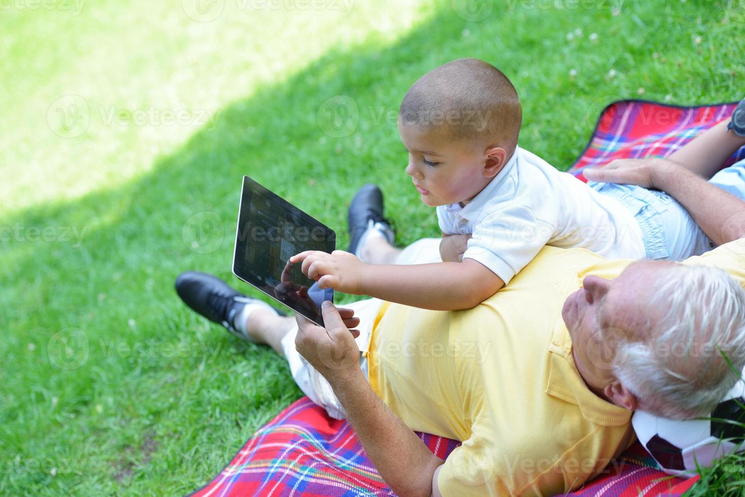 grandfather and child in park using tablet photo