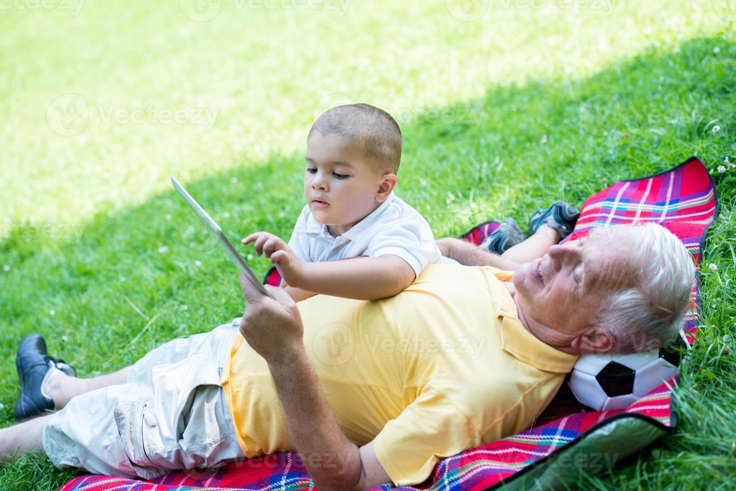 grandfather and child in park using tablet photo