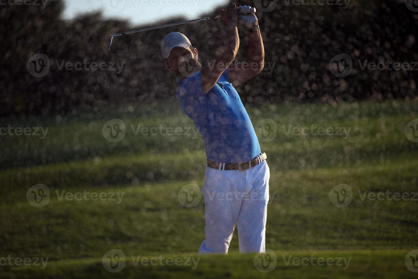 golfer hitting a sand bunker shot on sunset photo