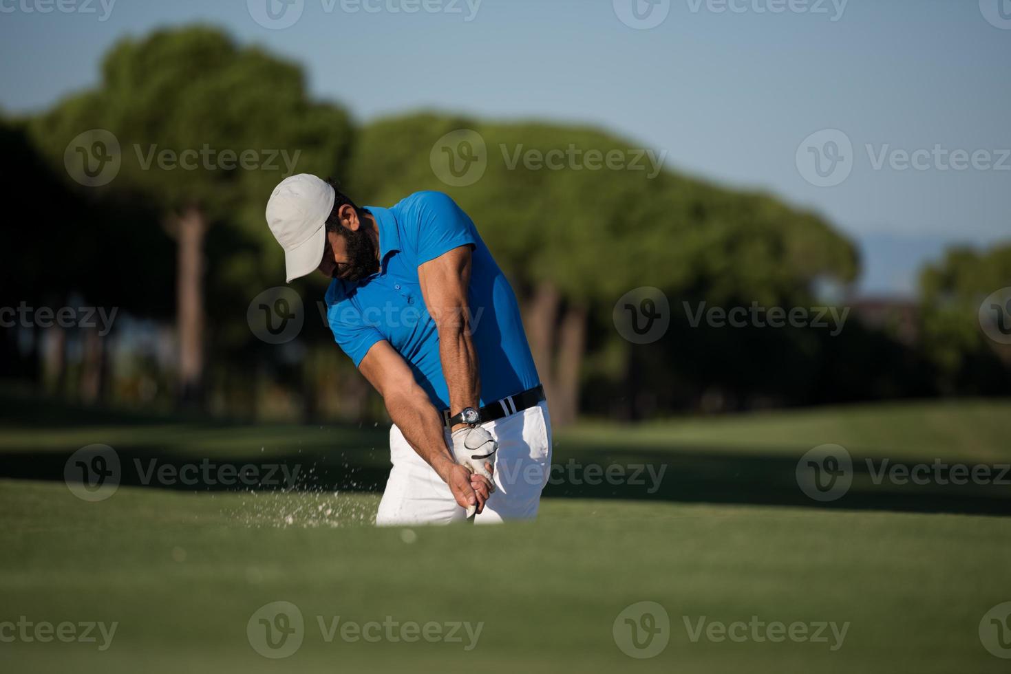 golfista profesional golpeando un tiro de búnker de arena foto