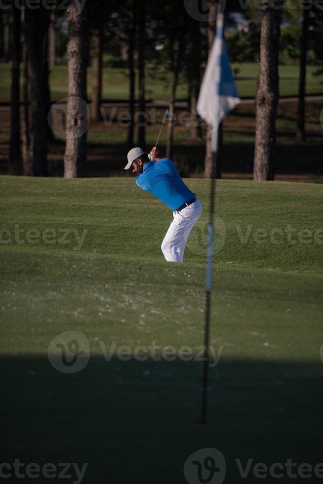 golfista profesional golpeando un tiro de búnker de arena foto