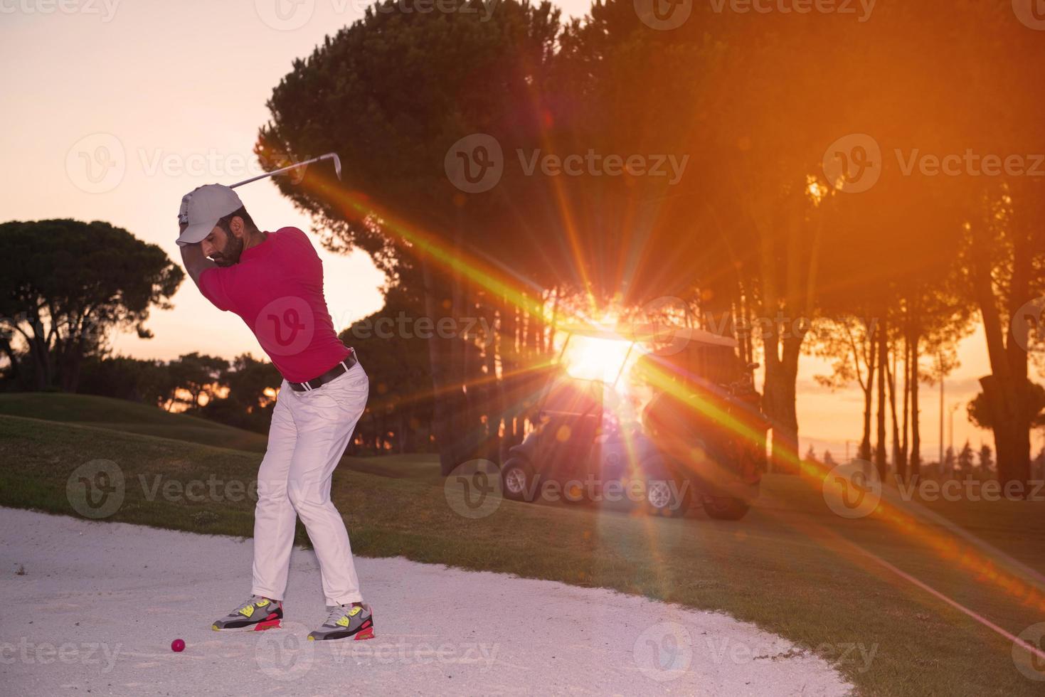 golfer hitting a sand bunker shot on sunset photo