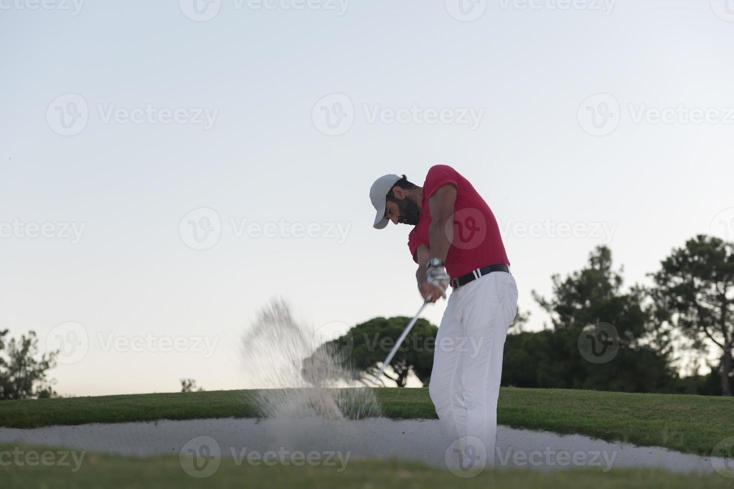 golfer hitting a sand bunker shot on sunset photo