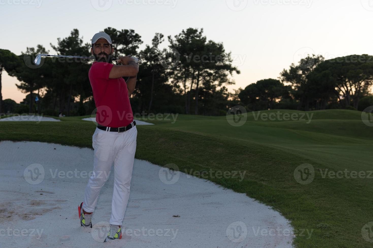 golfer hitting a sand bunker shot on sunset photo