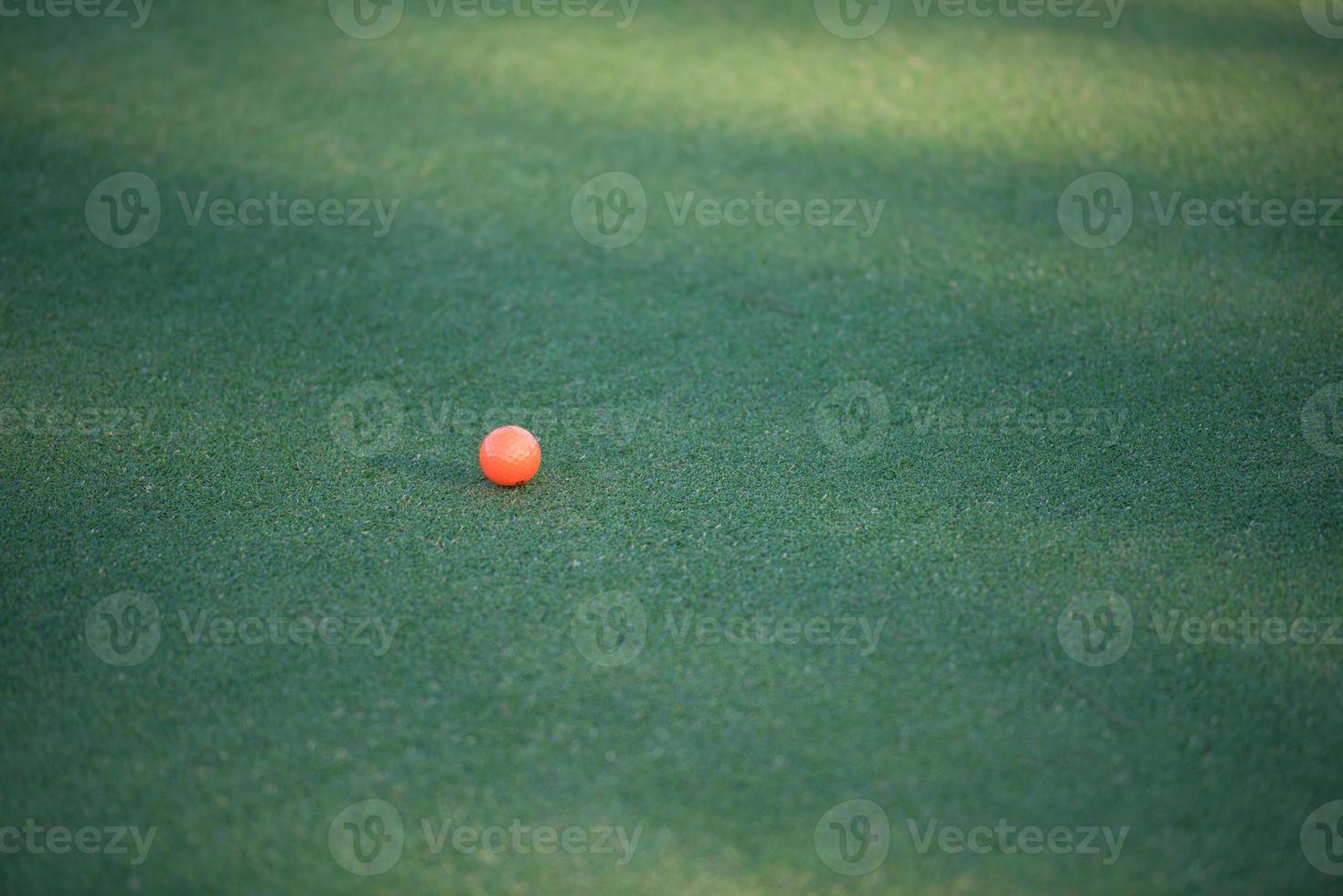 orange golf ball on grass photo