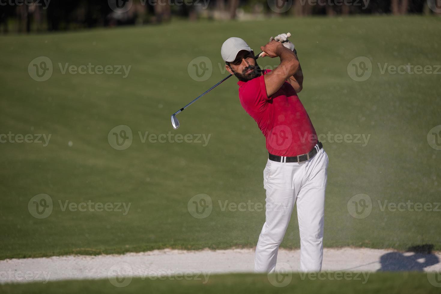 golfista golpeando un tiro de búnker de arena foto