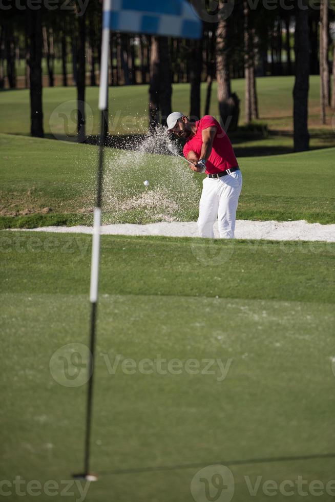 golfer hitting a sand bunker shot photo