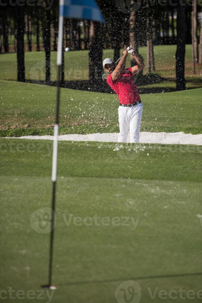 golfer hitting a sand bunker shot photo