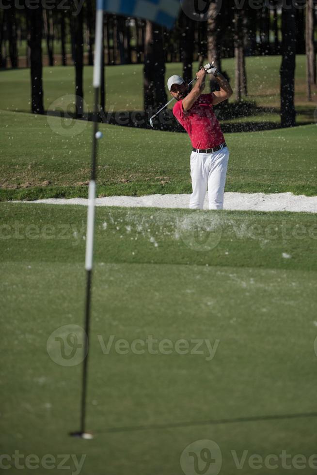 golfer hitting a sand bunker shot photo