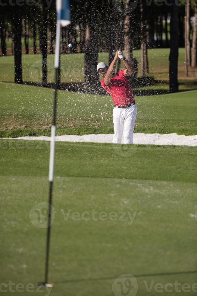 golfer hitting a sand bunker shot photo