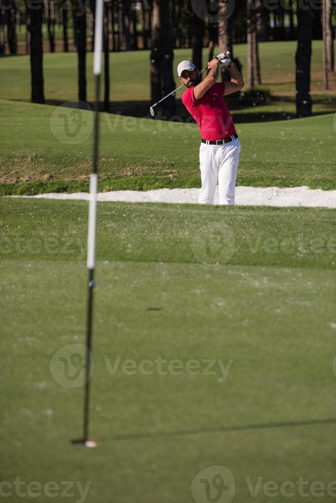 golfer hitting a sand bunker shot photo