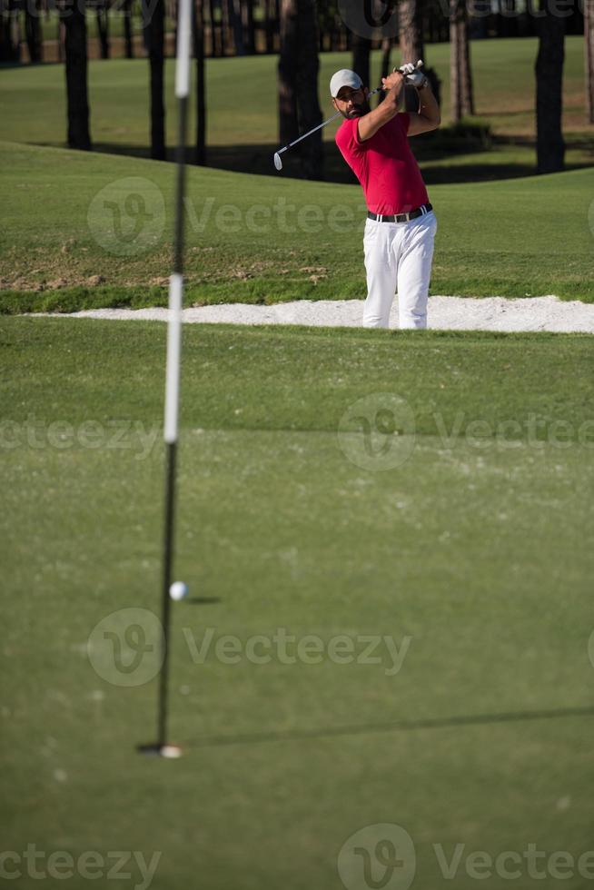 golfer hitting a sand bunker shot photo