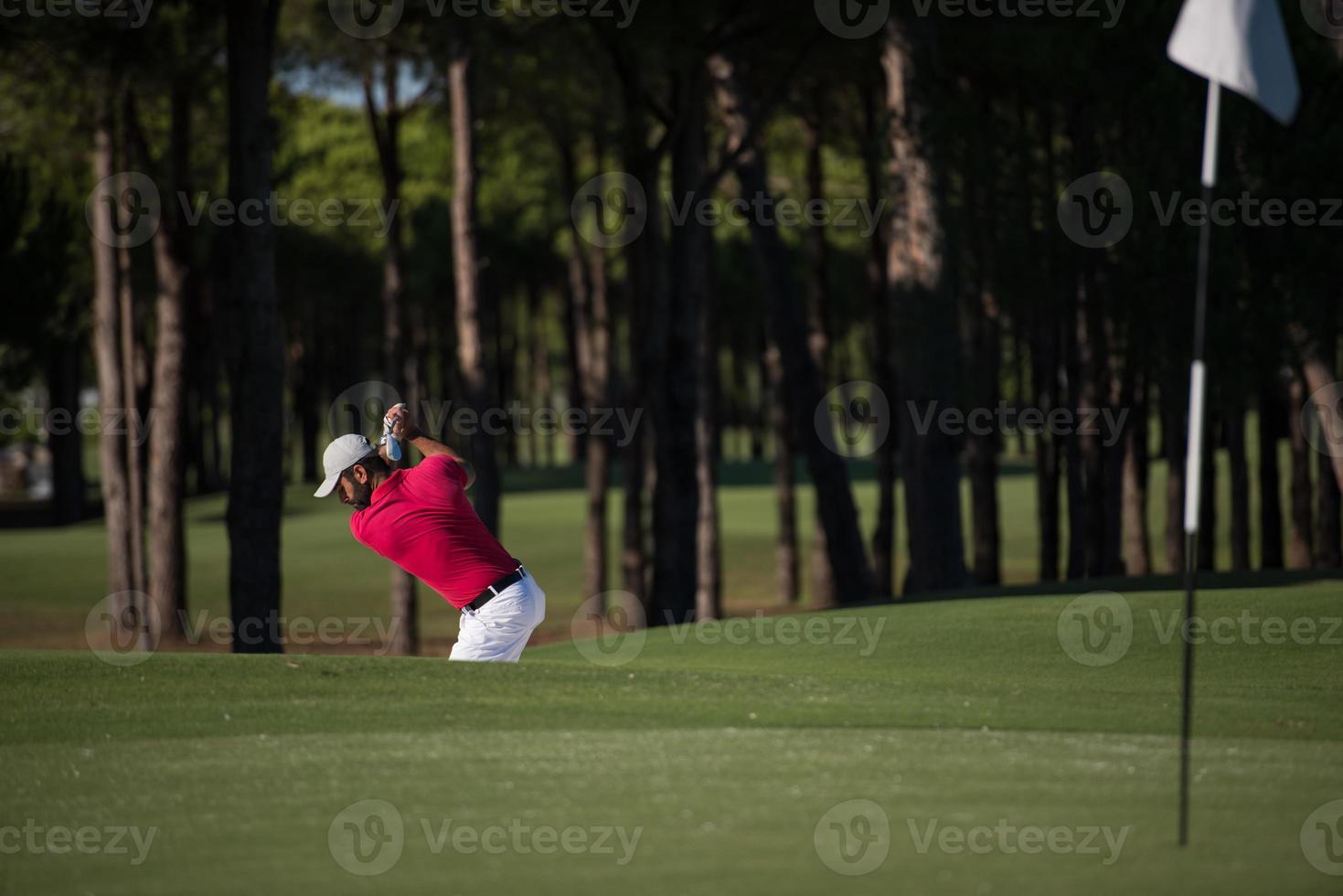 golfer hitting a sand bunker shot photo