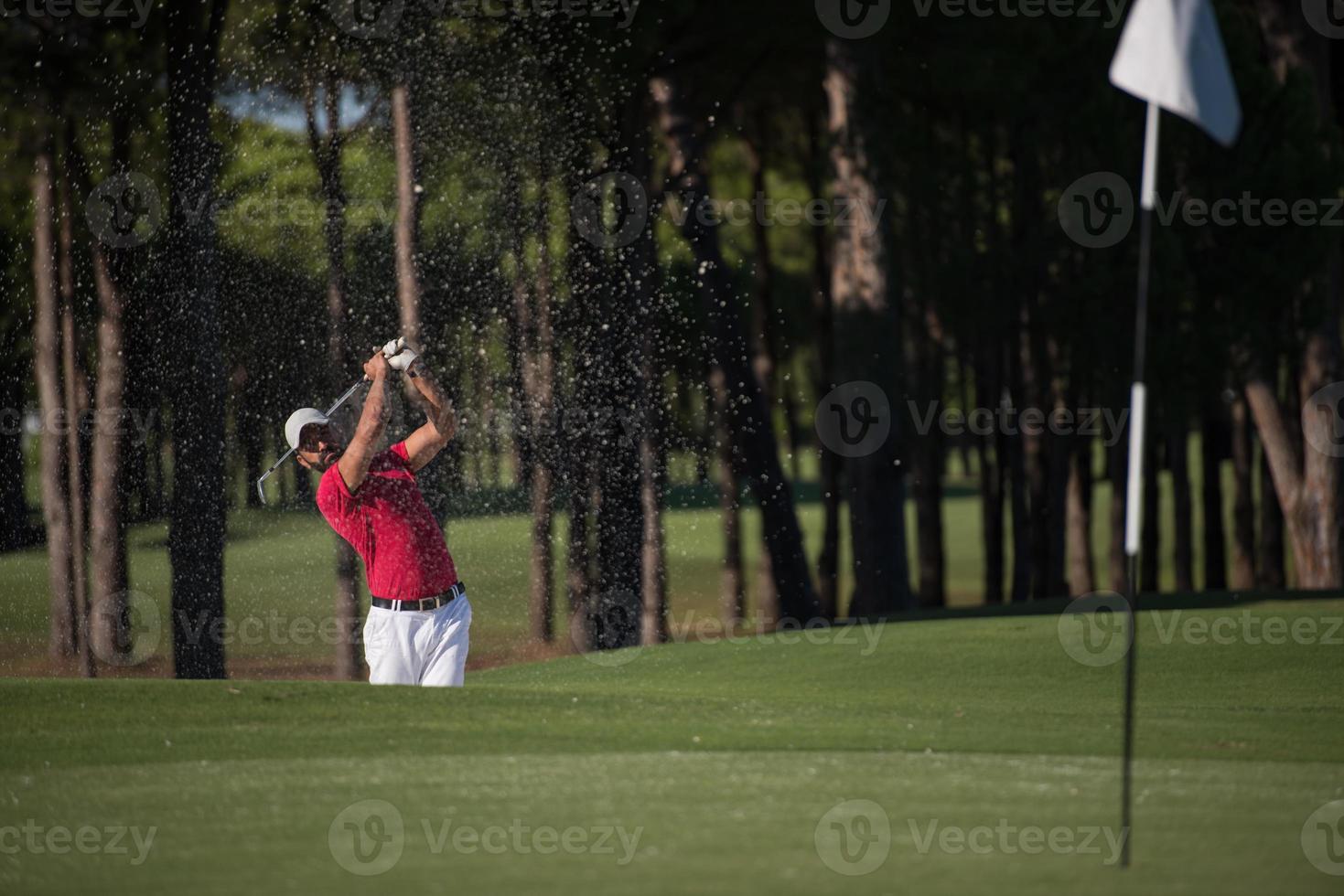 golfer hitting a sand bunker shot photo