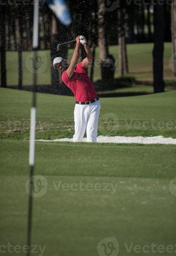 golfer hitting a sand bunker shot photo