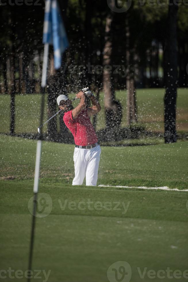 golfer hitting a sand bunker shot photo