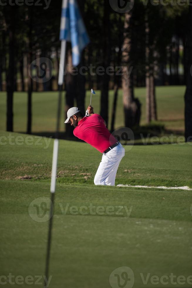 golfer hitting a sand bunker shot photo