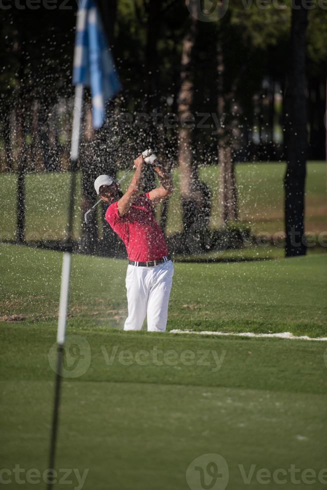 golfer hitting a sand bunker shot photo