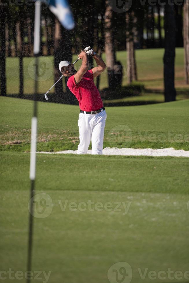 golfer hitting a sand bunker shot photo