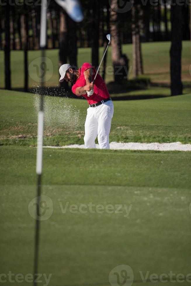 golfer hitting a sand bunker shot photo