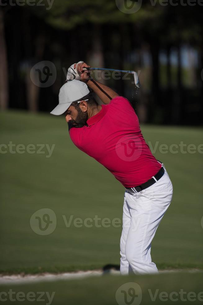 golfista golpeando un tiro de búnker de arena foto