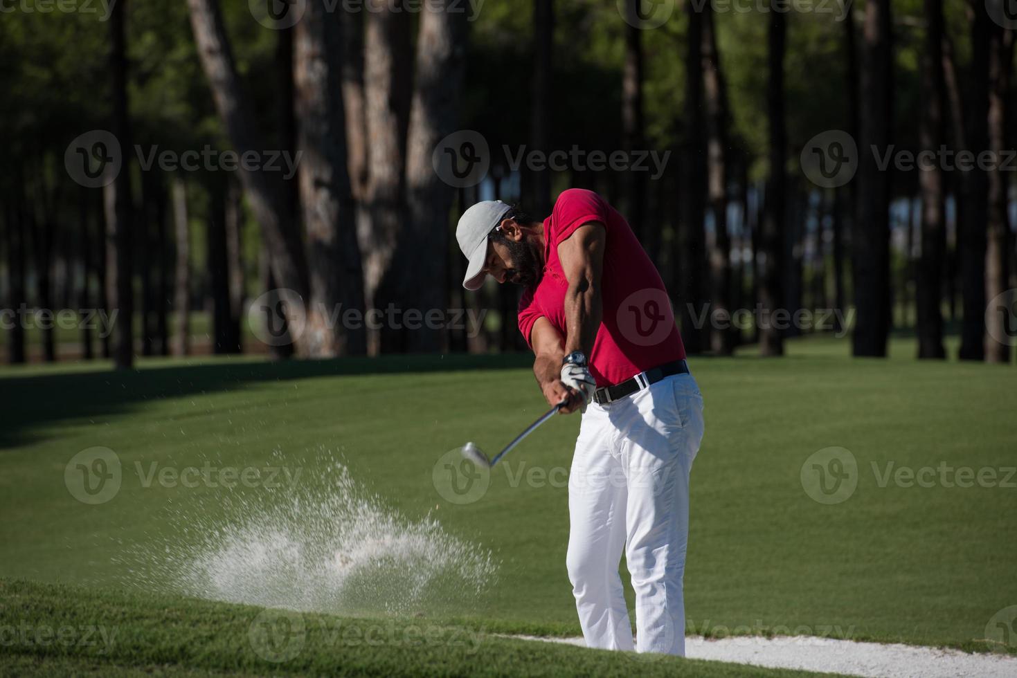 golfista golpeando un tiro de búnker de arena foto